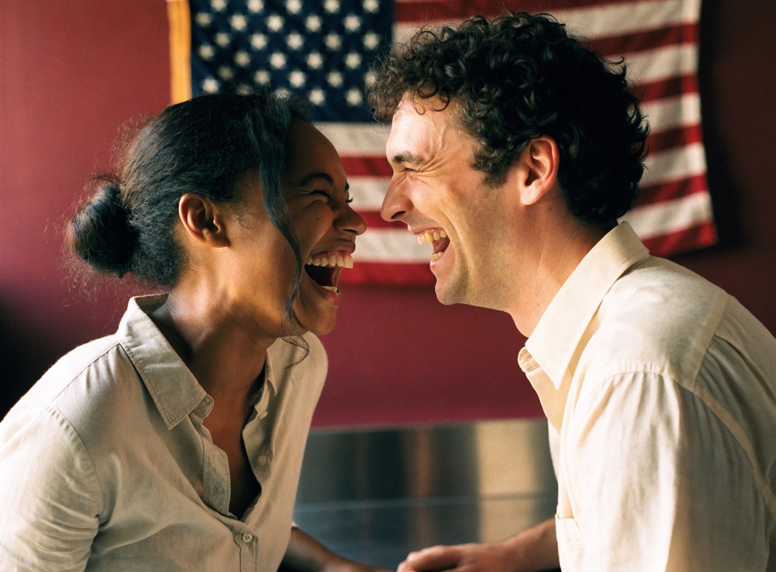 Two Tomorrow colleagues laughing together in the lab, a United States flag on the wall behind them